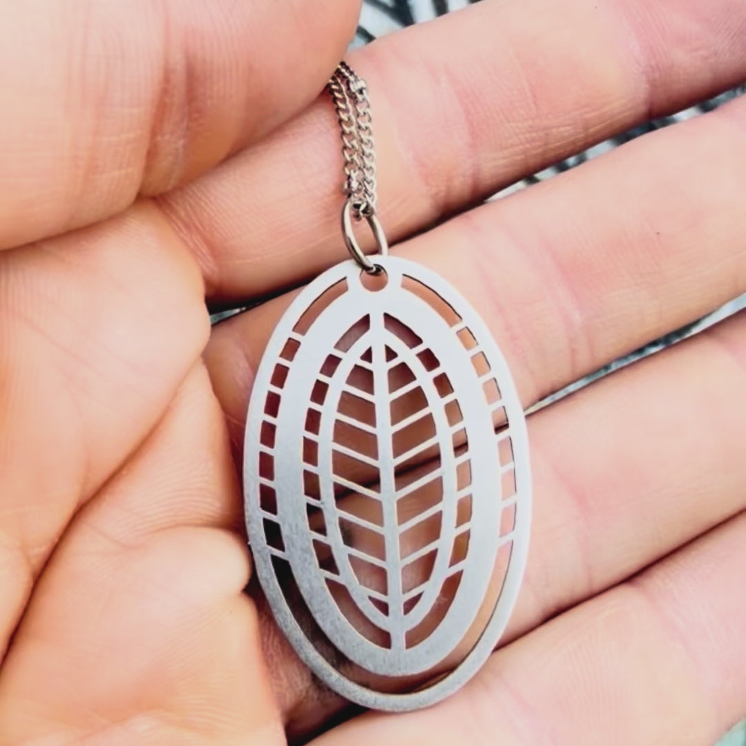 Stainless steel leaf pendant with textured background. 