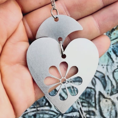 Stainless steel blooming heart pendant with textured background. 