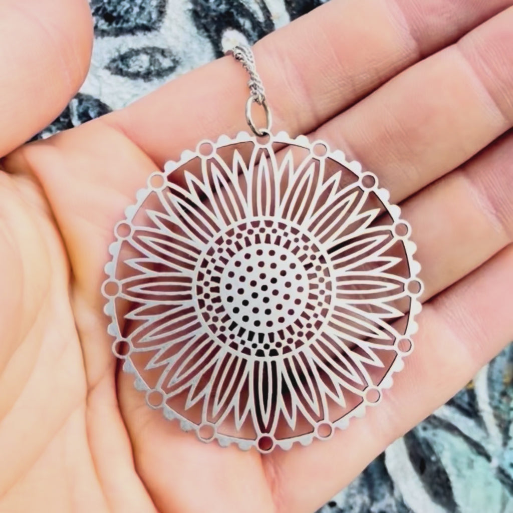 Stainless steel sunflower mandal pendant with textured background. 
